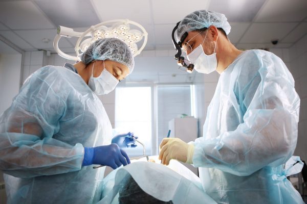 Dentysta Rzeszów wykonujący zabieg chirurgiczny na pacjencie.